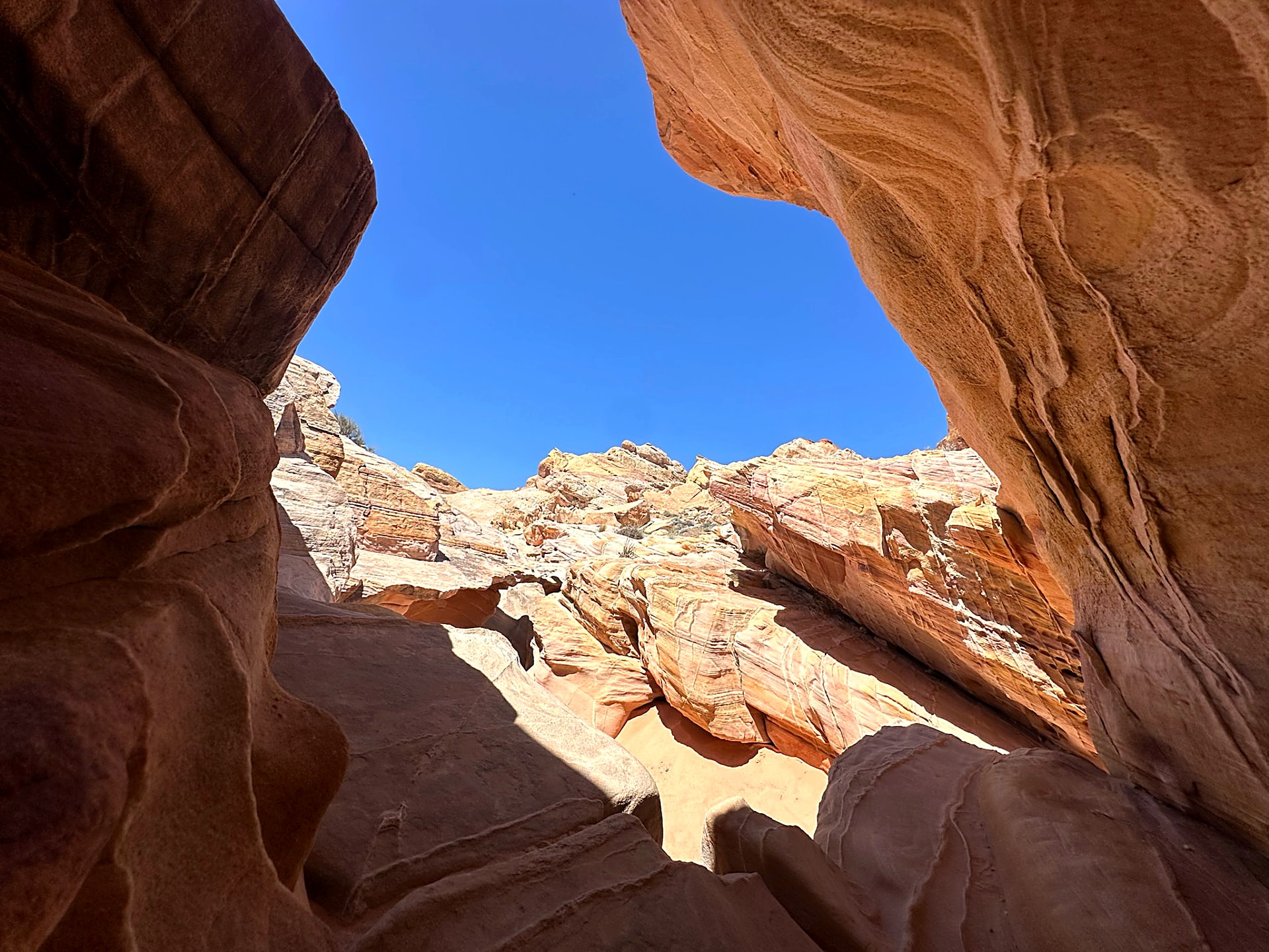 Dark red rock framing a bright sandstone ridge and blue sky