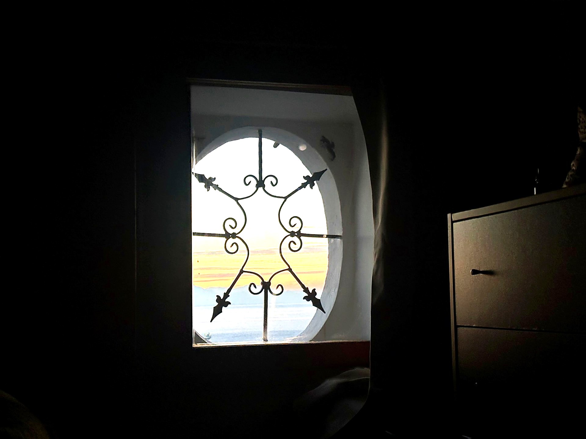 Sunrise seen through an arched window with decorative ironwork