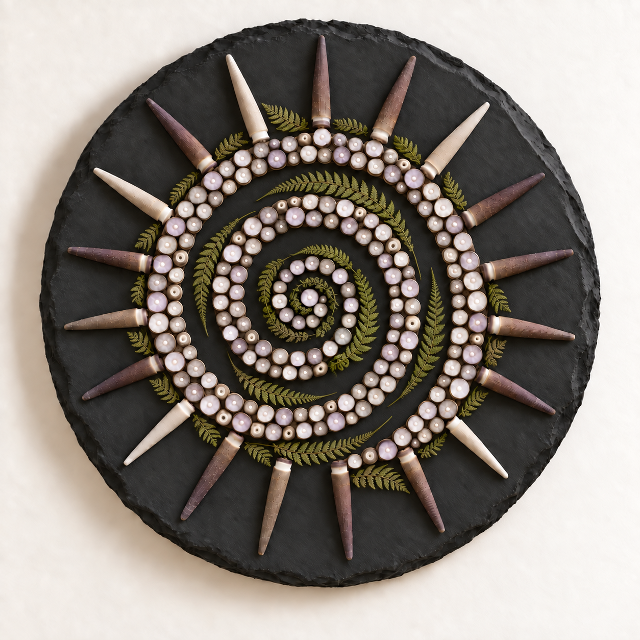 Round slate with a spiral of cut sea urchin spine rounds and preserved fern, ringed by whole urchin spines