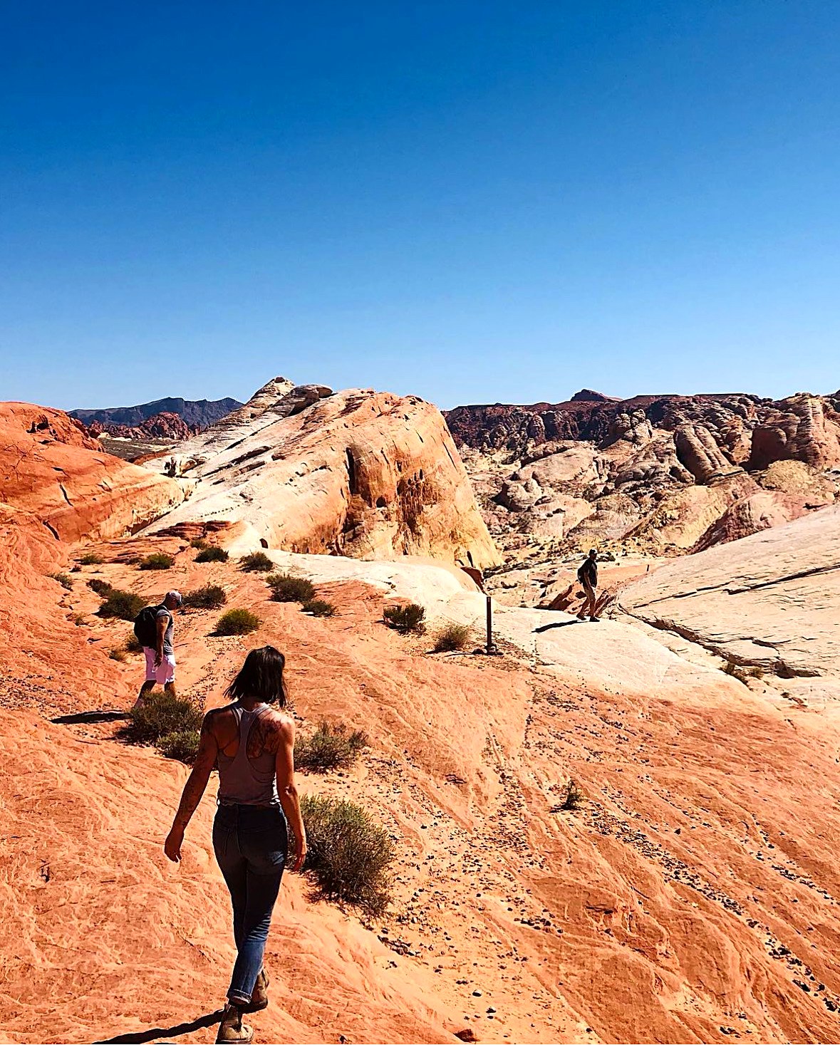 Esther hiking down red slickrock with other hikers ahead in the distance