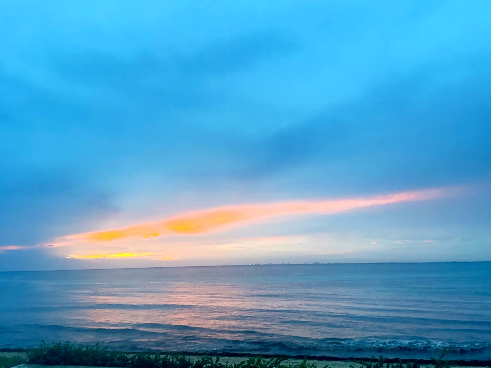 Blue dawn sky over the sea with one orange streak of cloud